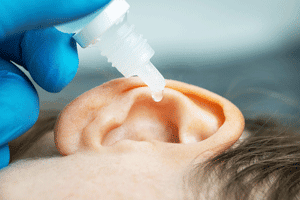 ear sidewys with hydrogen peroxide drops being administered by a hearing specialist